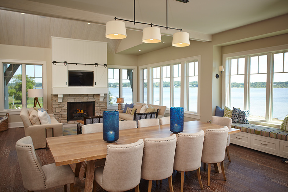 Mid-sized beach style open plan dining in Grand Rapids with beige walls, medium hardwood floors, a standard fireplace and a stone fireplace surround.