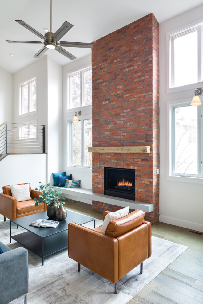 Inspiration for a large industrial open concept living room in Denver with white walls, medium hardwood floors, a standard fireplace, a brick fireplace surround, no tv and beige floor.