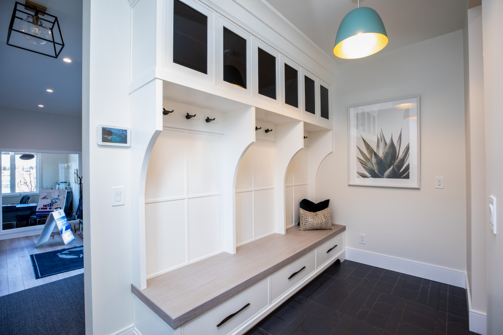Photo of a mid-sized country gender-neutral storage and wardrobe in Calgary with recessed-panel cabinets, white cabinets, ceramic floors and black floor.