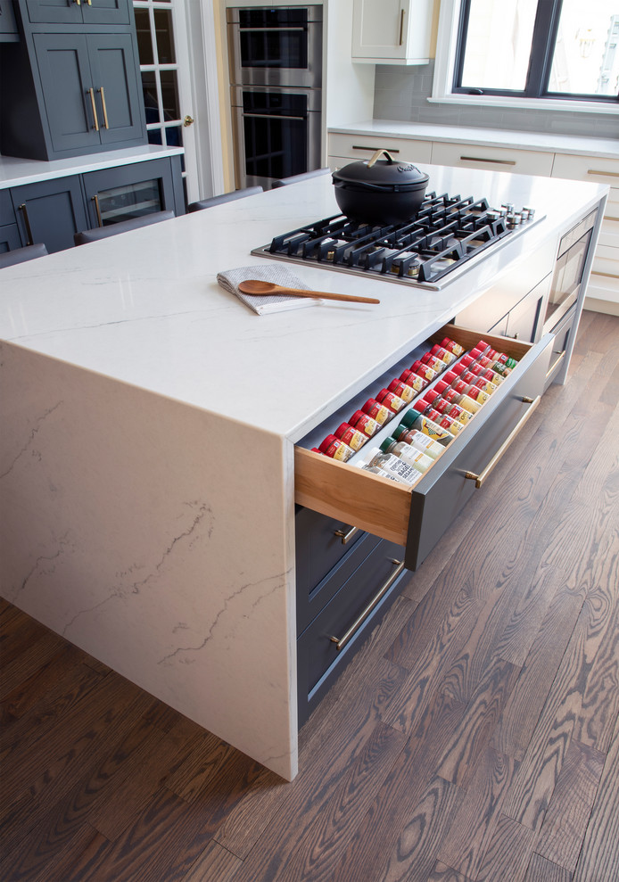 Inspiration for a large transitional u-shaped medium tone wood floor kitchen remodel with an undermount sink, gray cabinets, quartz countertops, gray backsplash, glass tile backsplash, stainless steel appliances, an island and white countertops