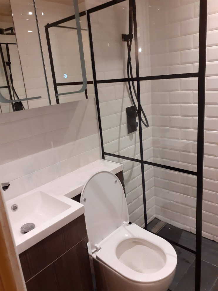 Inspiration för ett litet funkis vit vitt badrum med dusch, med släta luckor, skåp i mörkt trä, en öppen dusch, en vägghängd toalettstol, vit kakel, tunnelbanekakel, vita väggar, skiffergolv, ett integrerad handfat, bänkskiva i akrylsten, svart golv och med dusch som är öppen