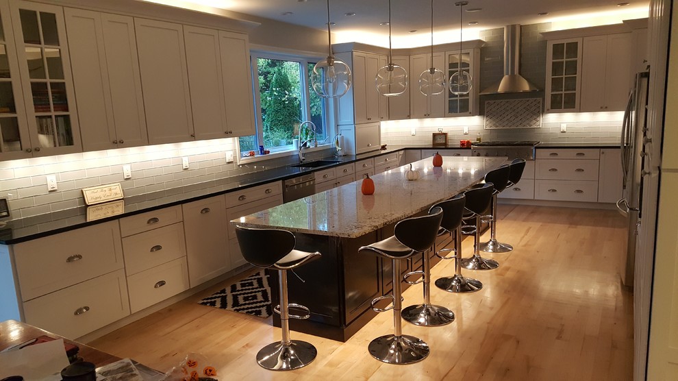 Eat-in kitchen - mid-sized transitional single-wall light wood floor and yellow floor eat-in kitchen idea with an undermount sink, shaker cabinets, white cabinets, quartz countertops, gray backsplash, glass tile backsplash, stainless steel appliances and an island
