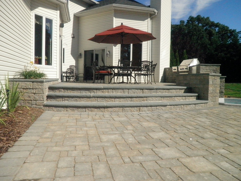 This is an example of a large traditional backyard patio in New York with an outdoor kitchen, concrete pavers and no cover.