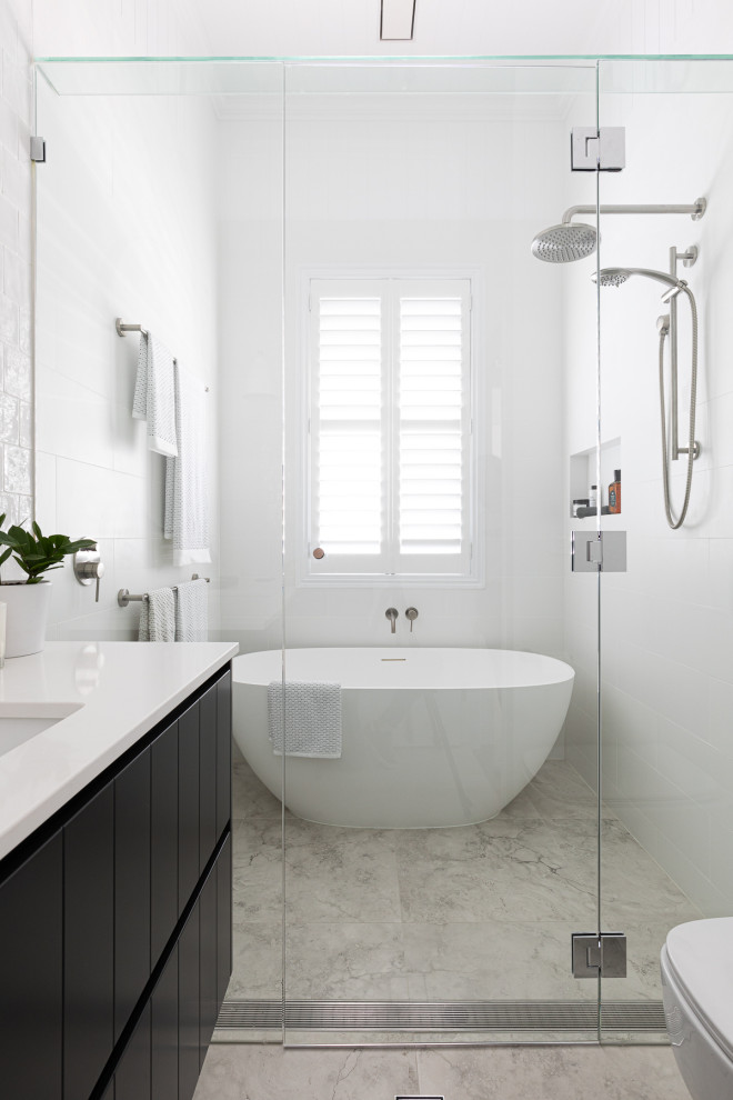 Transitional 3/4 wet room bathroom in Brisbane with black cabinets, a freestanding tub, white tile, white walls, an undermount sink, engineered quartz benchtops, grey floor, a hinged shower door, white benchtops, a single vanity, a built-in vanity and flat-panel cabinets.