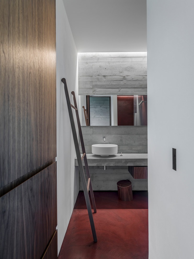 Photo of a small contemporary 3/4 bathroom in Other with medium wood cabinets, a curbless shower, a wall-mount toilet, concrete floors, a vessel sink, concrete benchtops, red floor and a hinged shower door.