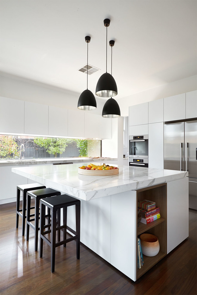Photo of a mid-sized contemporary kitchen in Melbourne with flat-panel cabinets, white cabinets, marble benchtops, white splashback, stainless steel appliances, dark hardwood floors and with island.