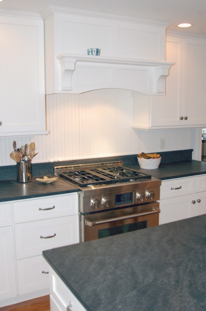 Photo of a mid-sized beach style kitchen in Boston with recessed-panel cabinets, white cabinets, granite benchtops, white splashback, stainless steel appliances, medium hardwood floors and with island.