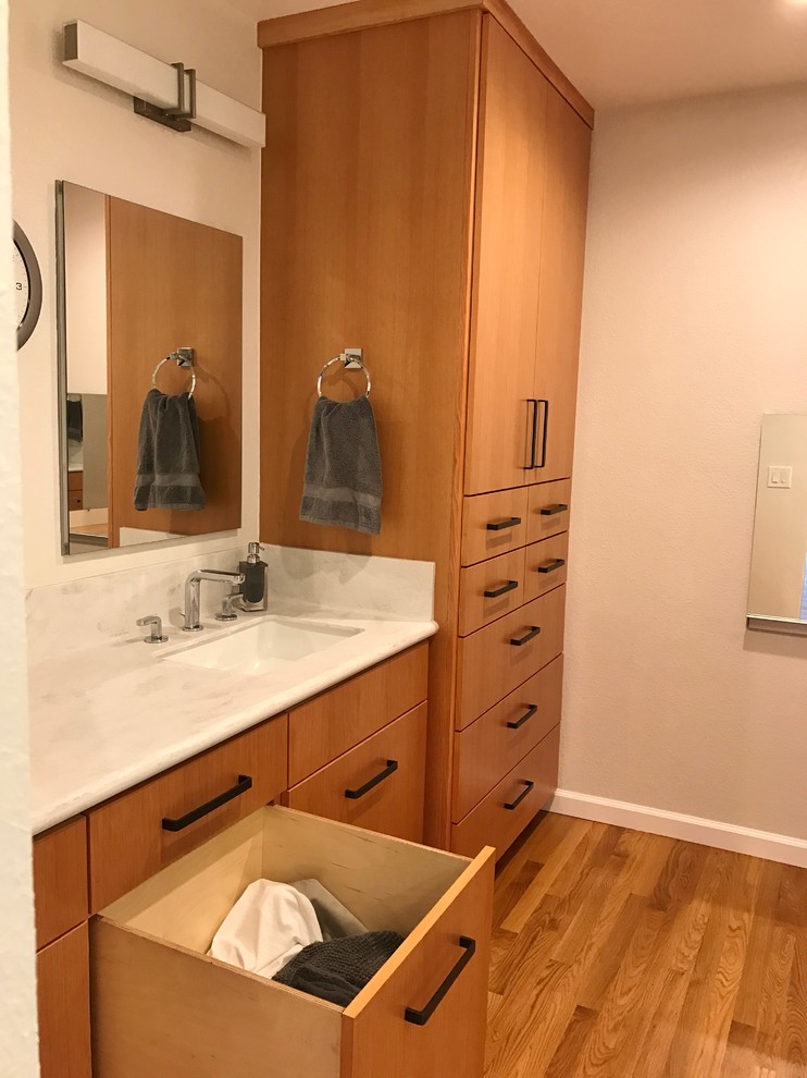 Inspiration for a mid-sized asian master wet room bathroom in San Francisco with flat-panel cabinets, medium wood cabinets, a one-piece toilet, beige walls, medium hardwood floors, an integrated sink and solid surface benchtops.