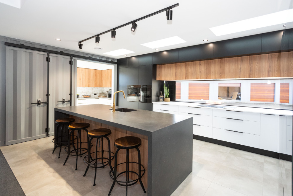 Large modern galley kitchen/diner in Other with a single-bowl sink, concrete worktops, black appliances, ceramic flooring, an island and grey worktops.