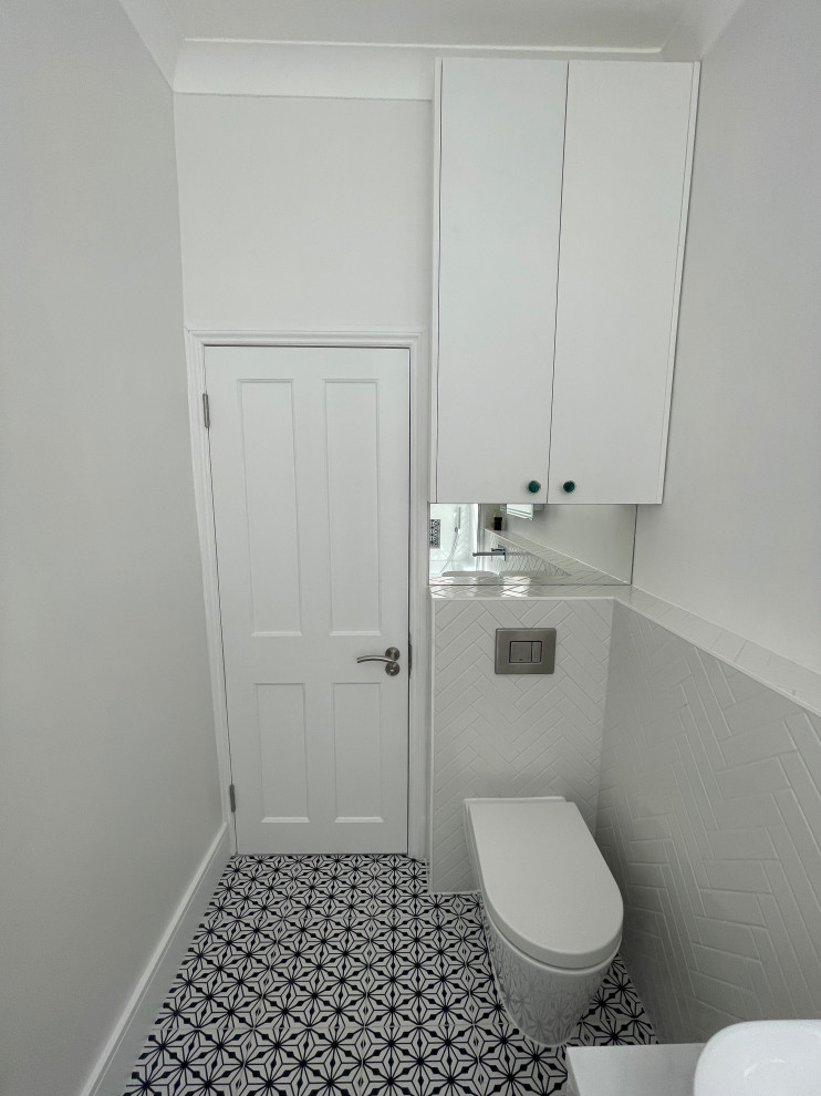 Exemple d'une salle de bain tendance de taille moyenne pour enfant avec un placard à porte plane, des portes de placard blanches, un bain japonais, un combiné douche/baignoire, WC suspendus, un carrelage blanc, des carreaux de porcelaine, un mur blanc, un sol en carrelage de céramique, une vasque, un plan de toilette en quartz, un sol noir, une cabine de douche à porte battante, un plan de toilette gris, meuble simple vasque et meuble-lavabo suspendu.