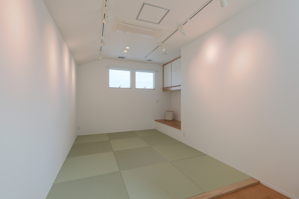 Ejemplo de habitación de invitados asiática grande con paredes blancas, tatami y suelo verde
