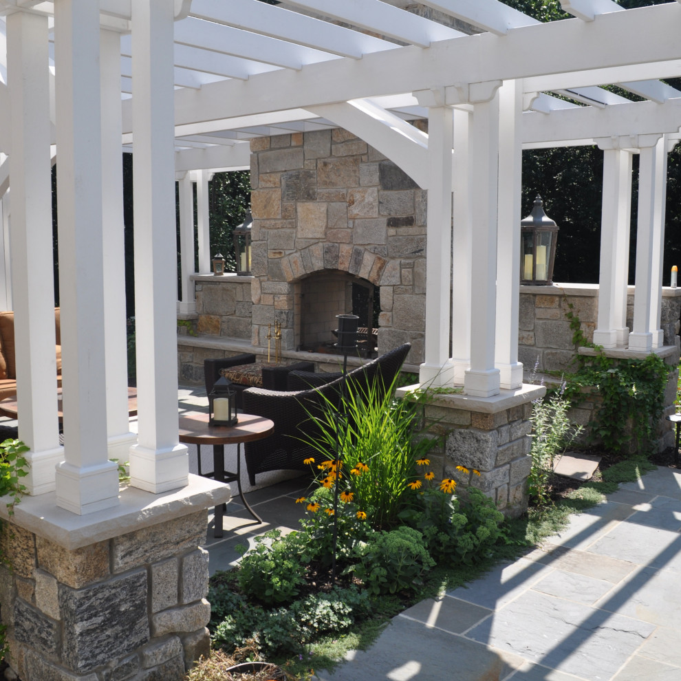 This is an example of a traditional backyard full sun formal garden in Chicago with with fireplace and natural stone pavers.