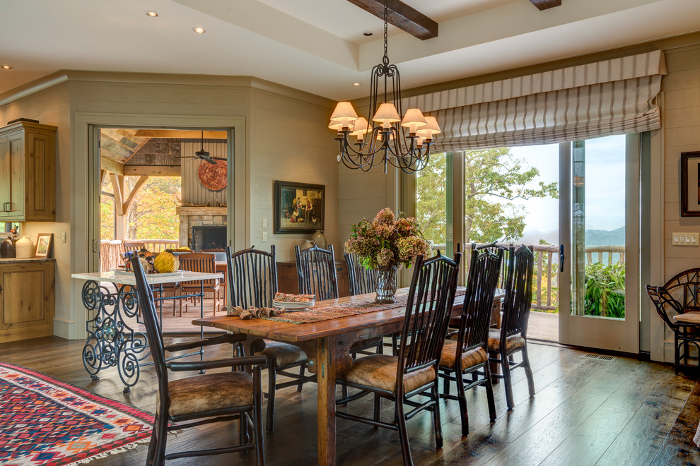 Photo of a large country open plan dining in Other with beige walls, dark hardwood floors, a standard fireplace and a stone fireplace surround.