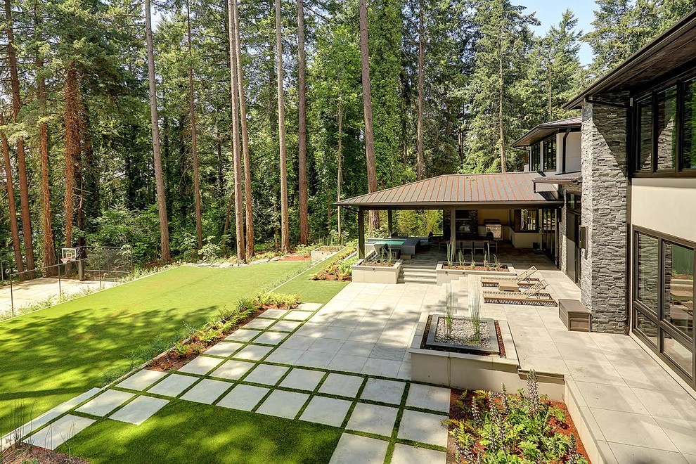 This is an example of a large contemporary backyard patio in Portland with an outdoor kitchen, concrete pavers and a roof extension.