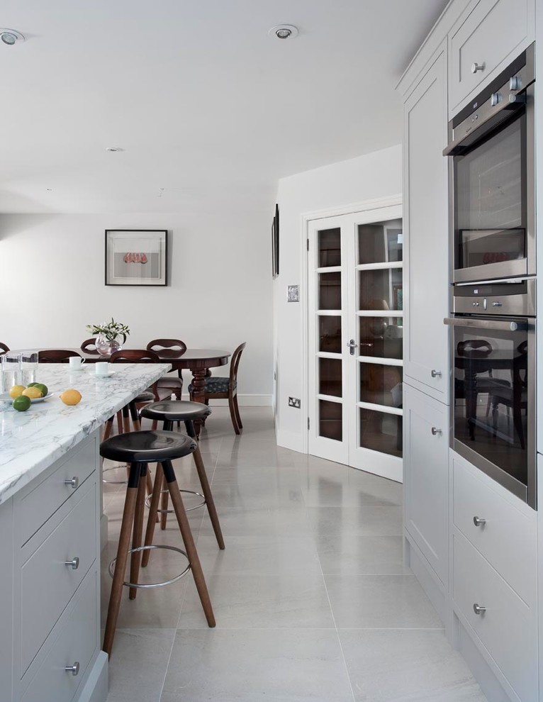 Inspiration for a mid-sized traditional eat-in kitchen in Dublin with an integrated sink, shaker cabinets, grey cabinets, marble benchtops, grey splashback, stone slab splashback, stainless steel appliances, terra-cotta floors and with island.