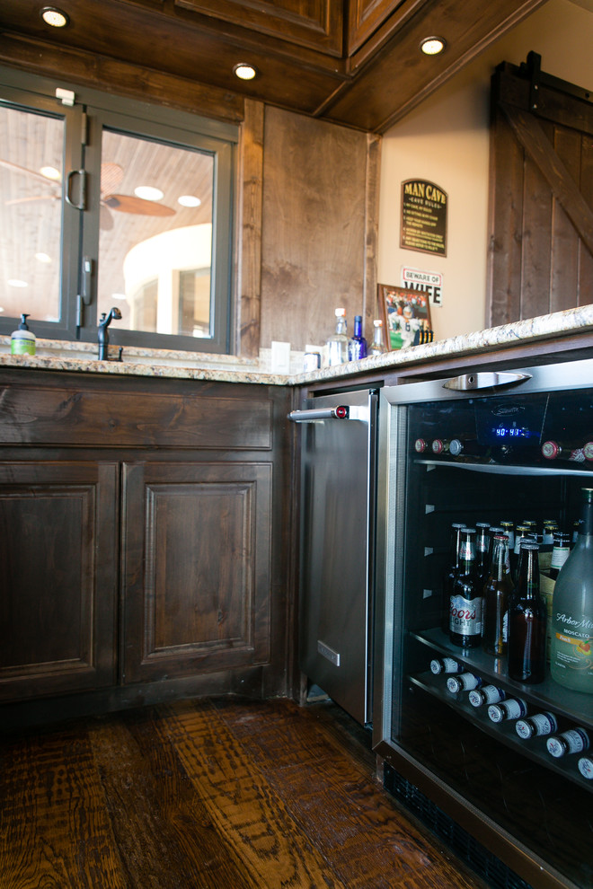 Inspiration for a mid-sized country seated home bar in Dallas with an undermount sink, raised-panel cabinets, dark wood cabinets, granite benchtops, dark hardwood floors and brown floor.