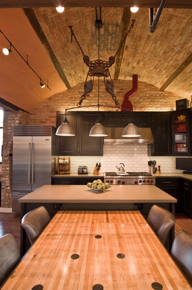 Inspiration for an industrial l-shaped kitchen remodel in Chicago with white backsplash and an island