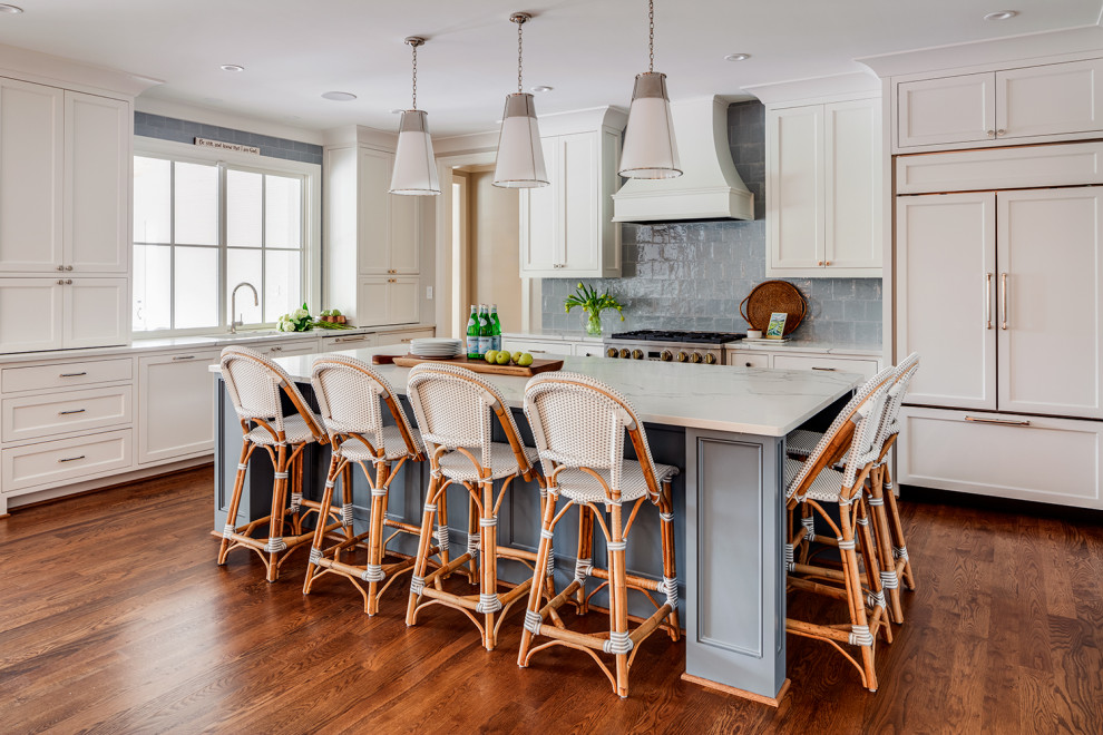 Large transitional l-shaped medium tone wood floor and brown floor eat-in kitchen photo with an integrated sink, shaker cabinets, white cabinets, quartzite countertops, blue backsplash, ceramic backsplash, paneled appliances, an island and white countertops