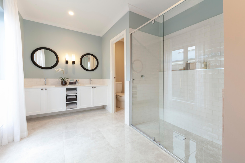 Photo of a large beach style master bathroom in Melbourne with white cabinets, a freestanding tub, a double shower, a one-piece toilet, white tile, ceramic tile, blue walls, ceramic floors, engineered quartz benchtops, beige floor, a hinged shower door, white benchtops, a double vanity and a floating vanity.