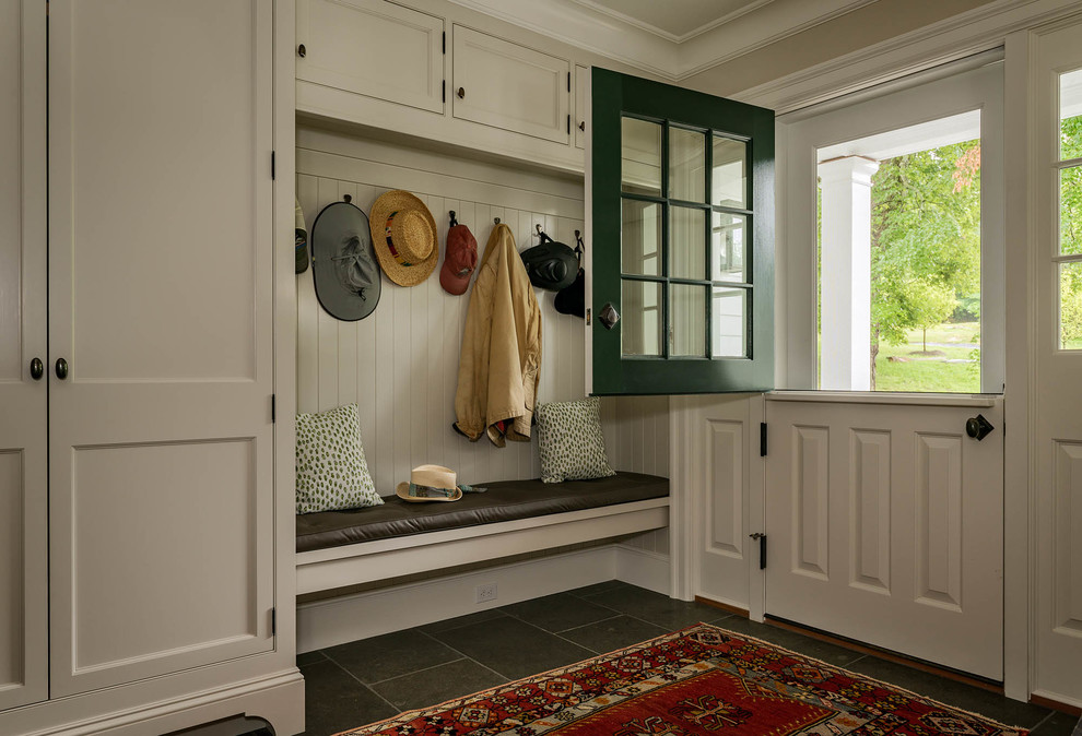 This is an example of a country mudroom in New York with beige walls, a dutch front door, a white front door and grey floor.