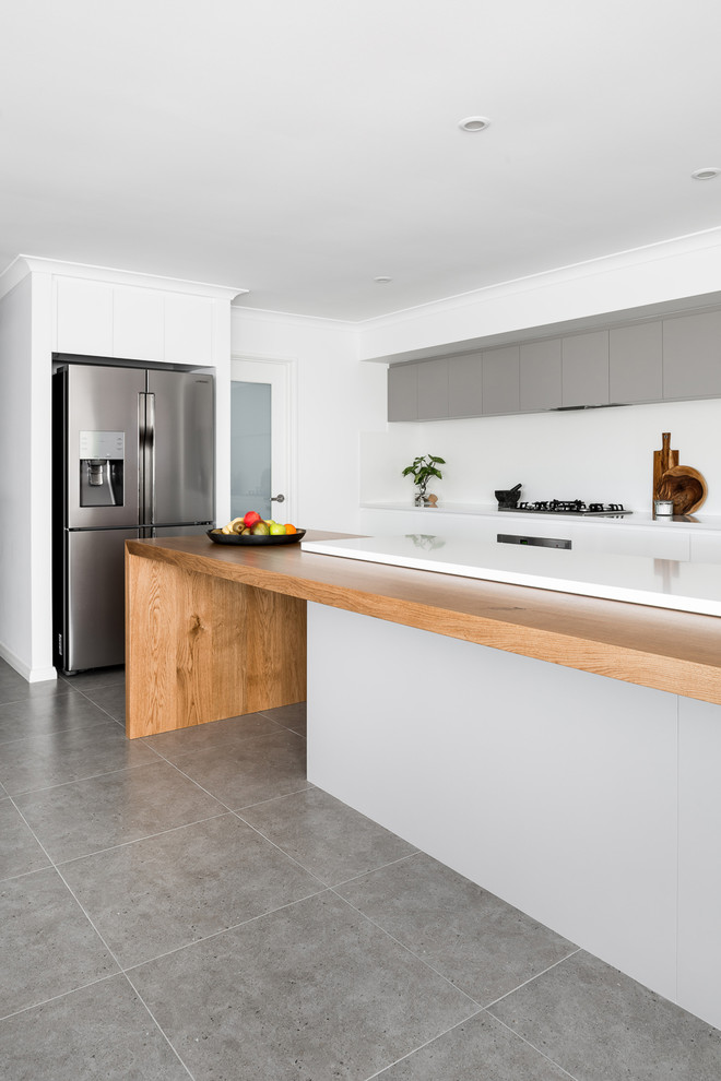 Inspiration for a large modern galley open plan kitchen in Perth with a drop-in sink, flat-panel cabinets, white cabinets, quartz benchtops, white splashback, porcelain splashback, stainless steel appliances, porcelain floors, with island and brown floor.