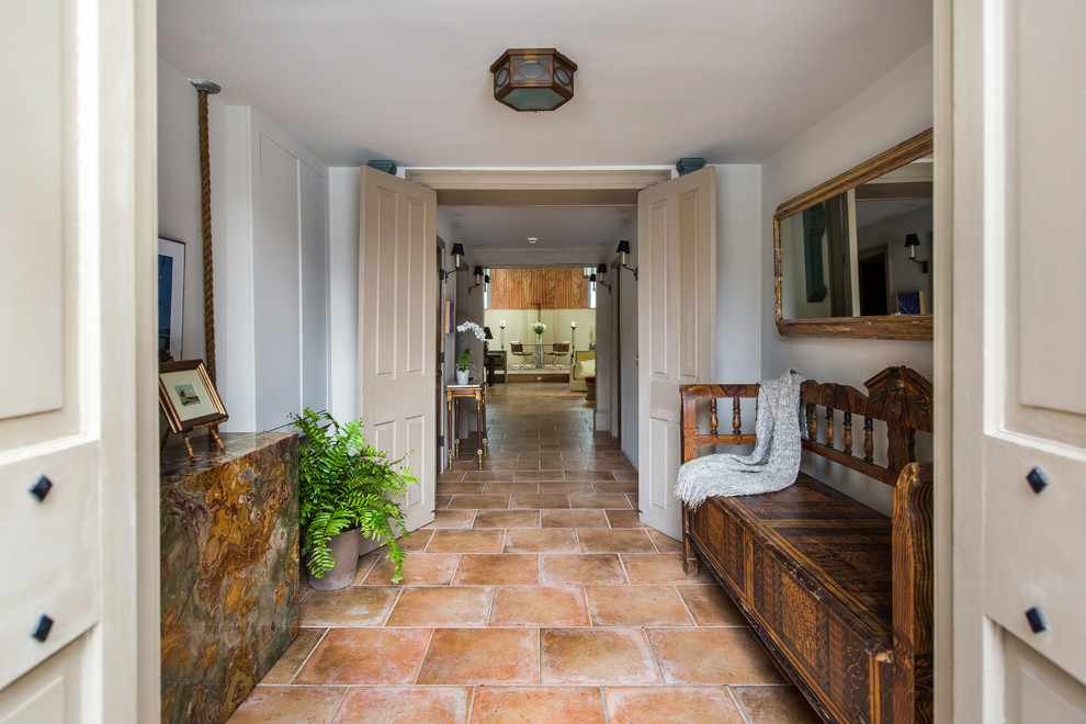 This is an example of a mid-sized traditional foyer in Philadelphia with white walls, travertine floors, a double front door, a blue front door and red floor.