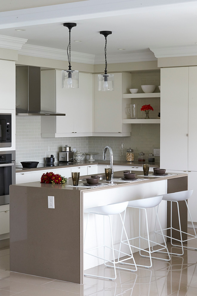Kitchen - transitional l-shaped kitchen idea in Toronto with an undermount sink, flat-panel cabinets, white cabinets, gray backsplash, subway tile backsplash, stainless steel appliances and an island