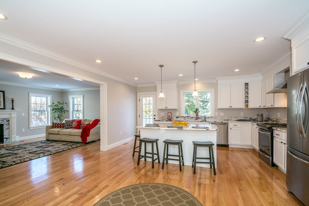 Large transitional l-shaped brown floor and medium tone wood floor eat-in kitchen photo in Boston with an undermount sink, recessed-panel cabinets, white cabinets, stone slab backsplash, stainless steel appliances, an island and quartzite countertops