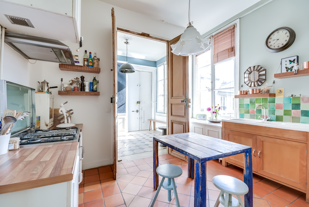 This is an example of a large eclectic galley separate kitchen in Paris with a double-bowl sink, shaker cabinets, light wood cabinets, multi-coloured splashback, mosaic tile splashback, terra-cotta floors and with island.