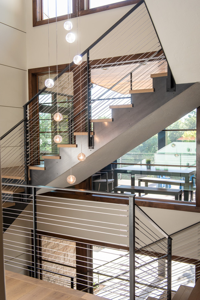 Large modern wood u-shaped staircase in Salt Lake City with open risers and cable railing.