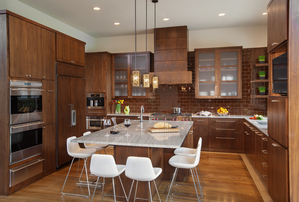 Large contemporary u-shaped eat-in kitchen in Austin with flat-panel cabinets, medium wood cabinets, quartzite benchtops, brown splashback, medium hardwood floors, with island, an undermount sink, subway tile splashback, panelled appliances and brown floor.