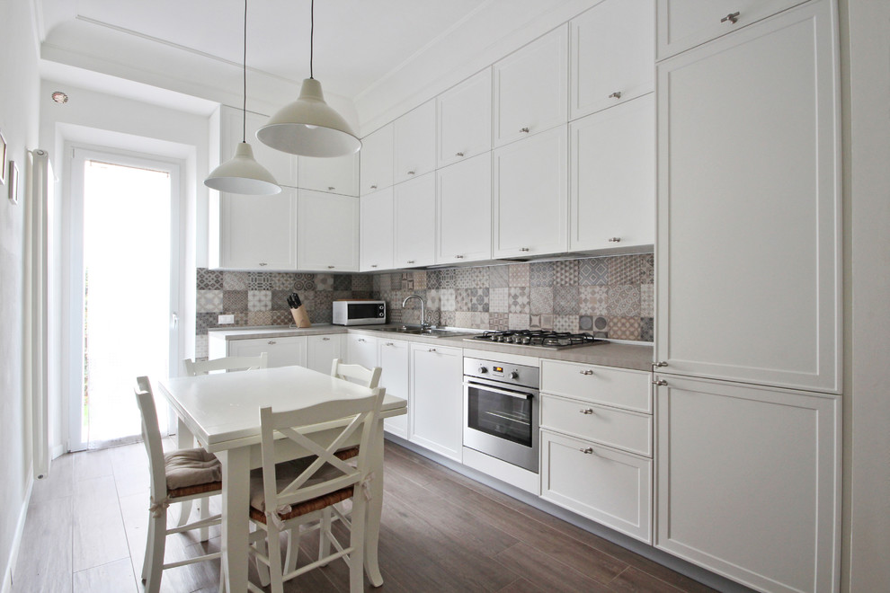 Inspiration for a mid-sized scandinavian l-shaped open plan kitchen in Other with recessed-panel cabinets, white cabinets, multi-coloured splashback, ceramic splashback, porcelain floors, no island, grey floor, a drop-in sink, quartzite benchtops, black appliances and pink benchtop.