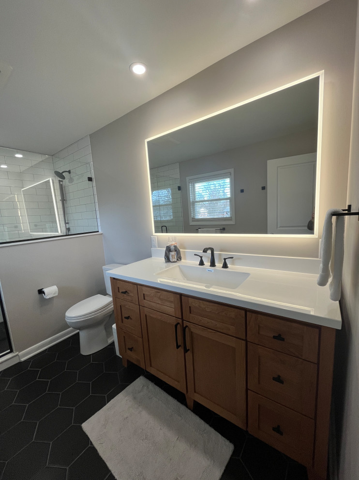 Mid-sized minimalist master white tile and subway tile porcelain tile, black floor and single-sink alcove shower photo in Indianapolis with shaker cabinets, light wood cabinets, a two-piece toilet, gray walls, an integrated sink, quartz countertops, a hinged shower door, white countertops, a niche and a freestanding vanity