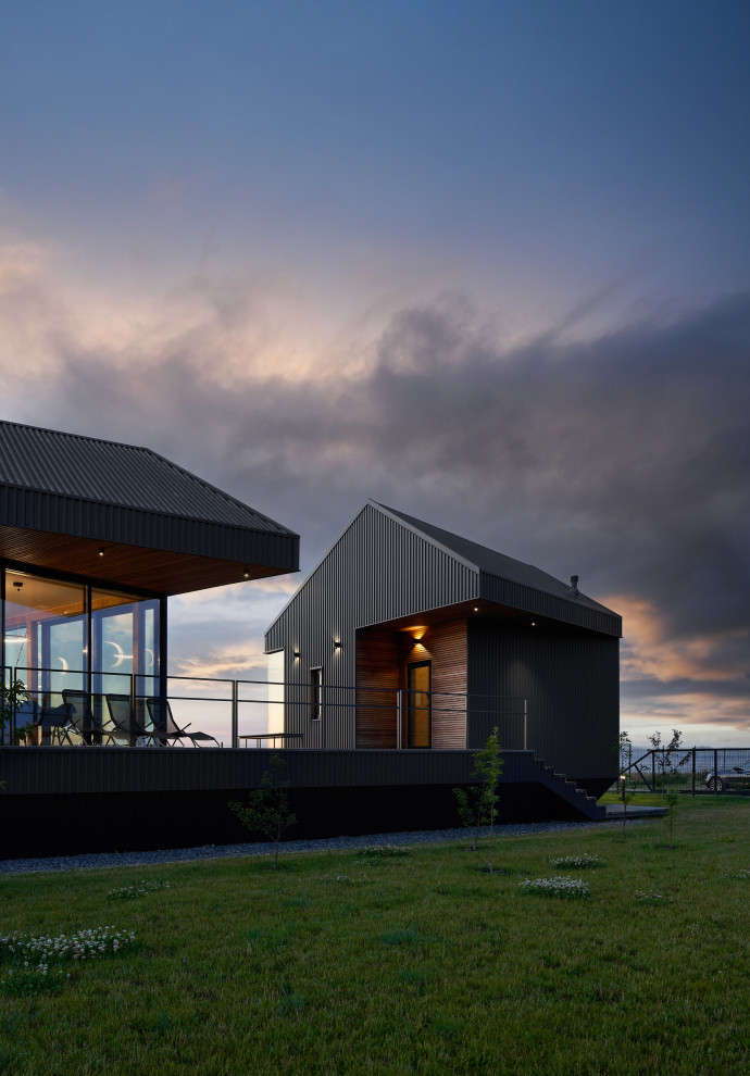 Cette photo montre une façade de maison métallique et grise scandinave de plain-pied avec un toit gris.