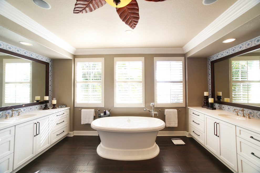 This is an example of a large modern master bathroom in San Diego with shaker cabinets, white cabinets, a freestanding tub, an alcove shower, a one-piece toilet, blue tile, ceramic tile, brown walls, dark hardwood floors, a drop-in sink, engineered quartz benchtops, brown floor, a hinged shower door and white benchtops.