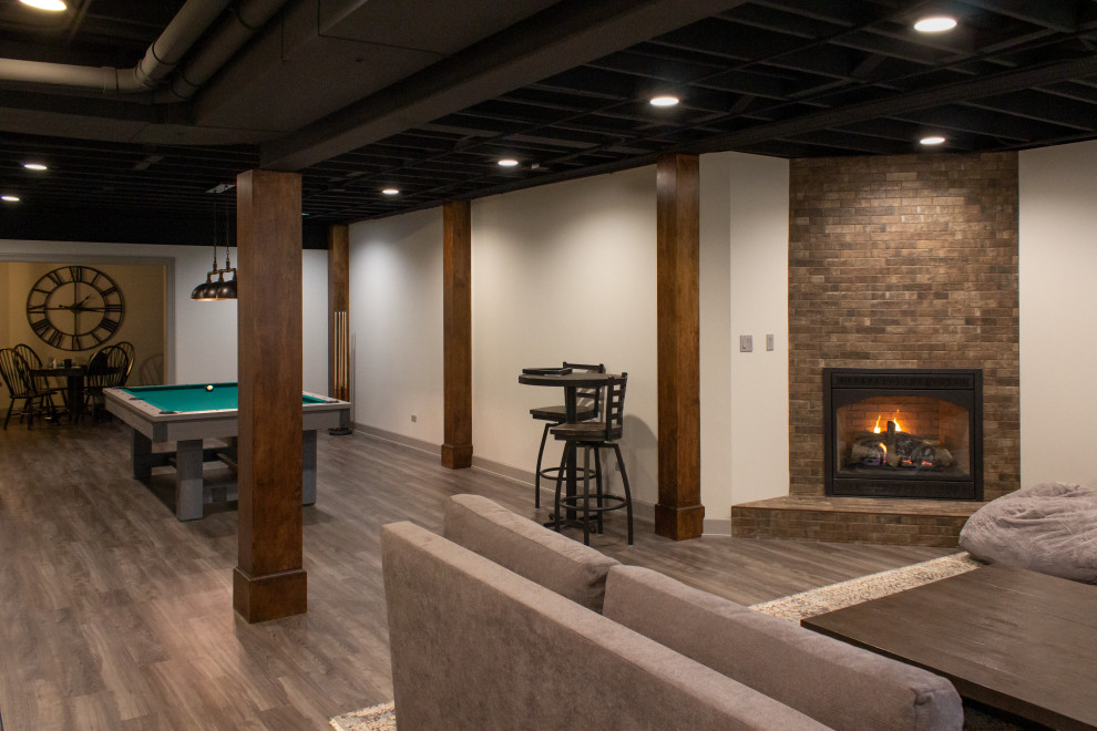Inspiration for a large industrial look-out basement in Chicago with a home bar, vinyl flooring, a corner fireplace, a brick fireplace surround and grey floors.