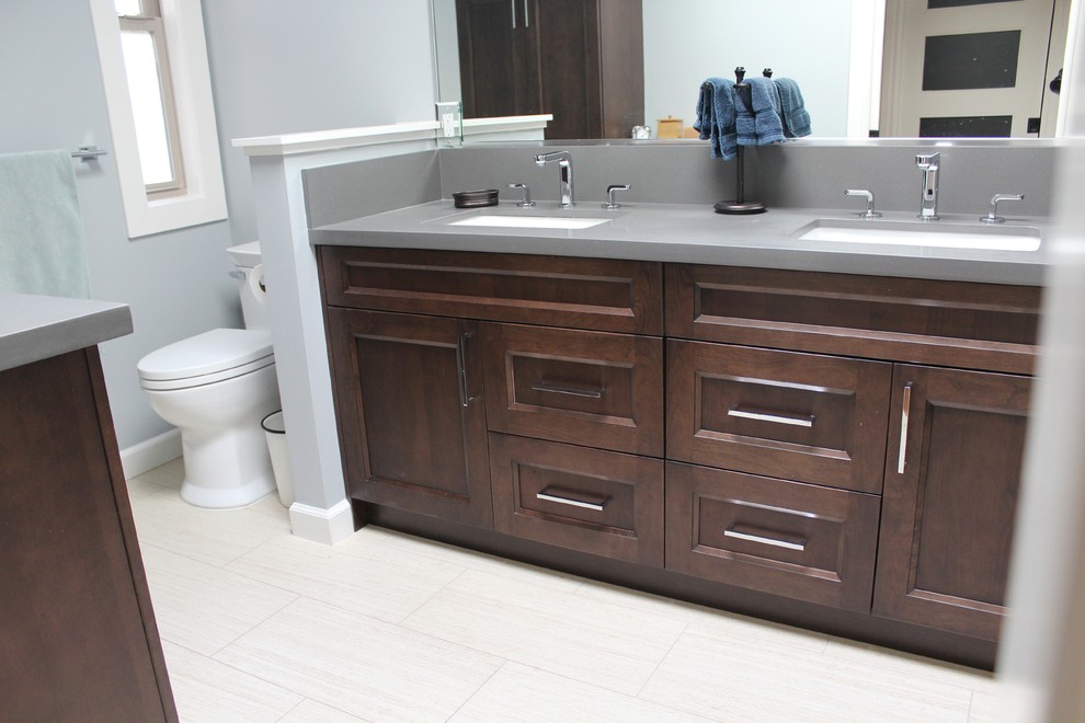 This is an example of a small modern master bathroom in San Francisco with recessed-panel cabinets, dark wood cabinets, a corner shower, a one-piece toilet, blue walls, porcelain floors, an undermount sink and engineered quartz benchtops.