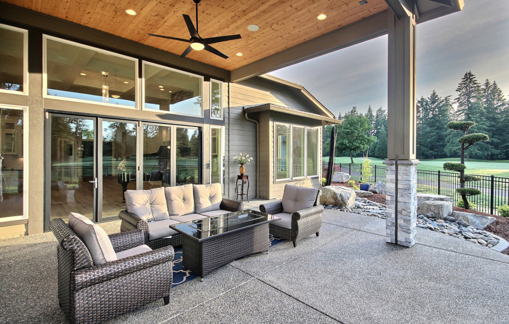Idee per un ampio patio o portico minimalista dietro casa con un focolare, lastre di cemento e un tetto a sbalzo