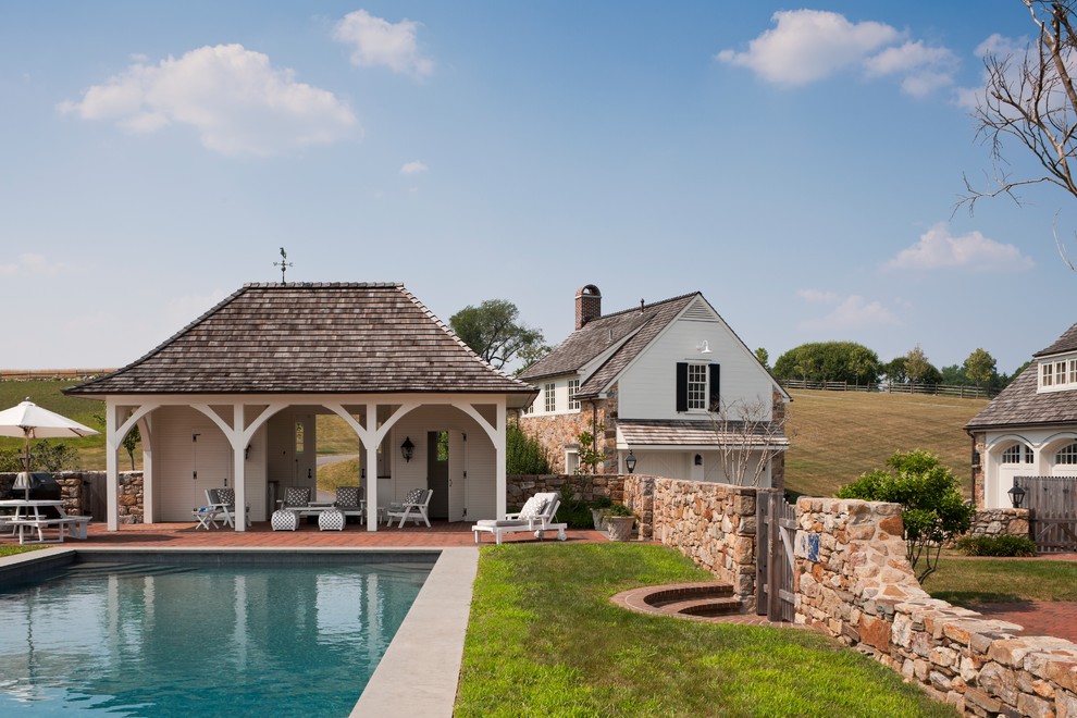 Photo of a country rectangular pool in Philadelphia with brick pavers and a pool house.