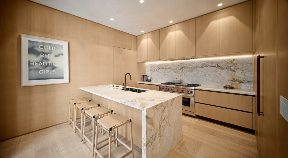 Example of a trendy l-shaped medium tone wood floor and brown floor kitchen design in Miami with an undermount sink, flat-panel cabinets, light wood cabinets, stainless steel appliances, a peninsula and gray countertops