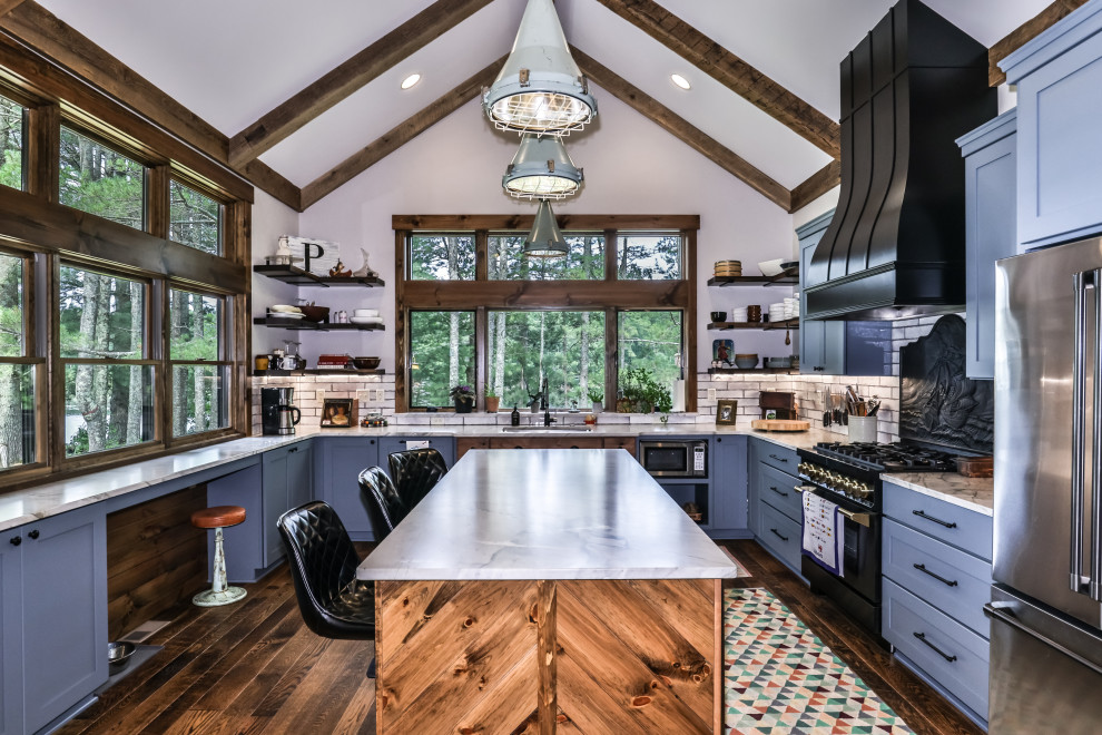 Inspiration for a mid-sized rustic u-shaped medium tone wood floor, brown floor and vaulted ceiling open concept kitchen remodel with an undermount sink, shaker cabinets, blue cabinets, quartzite countertops, white backsplash, ceramic backsplash, stainless steel appliances, an island and white countertops