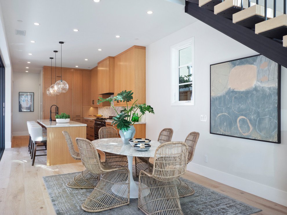 Immagine di una sala da pranzo aperta verso la cucina contemporanea con pareti grigie, parquet chiaro e pavimento beige
