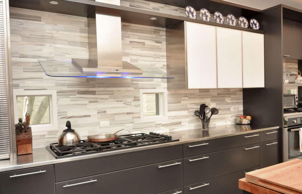 Photo of a large contemporary galley separate kitchen in Dallas with flat-panel cabinets, grey cabinets, stainless steel benchtops, grey splashback, stone tile splashback, stainless steel appliances and with island.