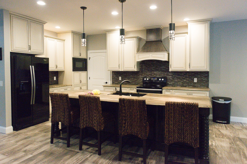 Example of a large transitional l-shaped ceramic tile eat-in kitchen design in Chicago with an undermount sink, raised-panel cabinets, dark wood cabinets, marble countertops, brown backsplash, glass tile backsplash, black appliances and an island