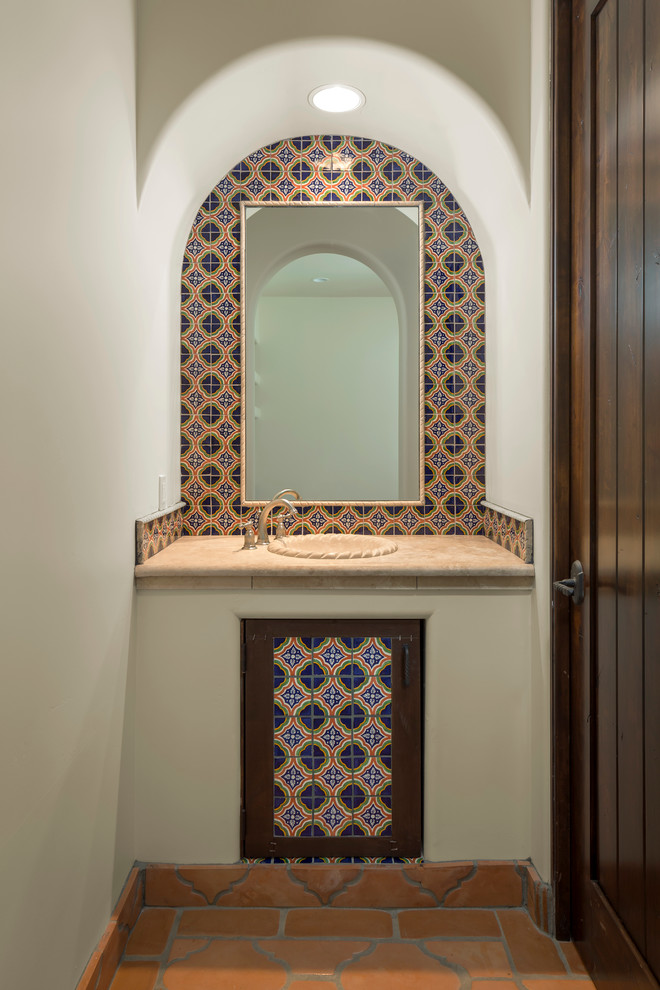 Photo of a mid-sized mediterranean powder room in Phoenix with a drop-in sink, multi-coloured tile, white walls, terra-cotta floors, dark wood cabinets, ceramic tile and beige benchtops.