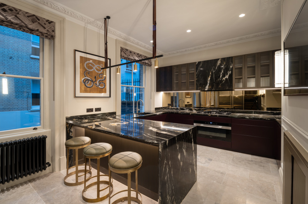 This is an example of a mid-sized traditional u-shaped kitchen in London with an undermount sink, flat-panel cabinets, dark wood cabinets, marble benchtops, metallic splashback, mirror splashback, stainless steel appliances, marble floors, with island, beige floor and black benchtop.