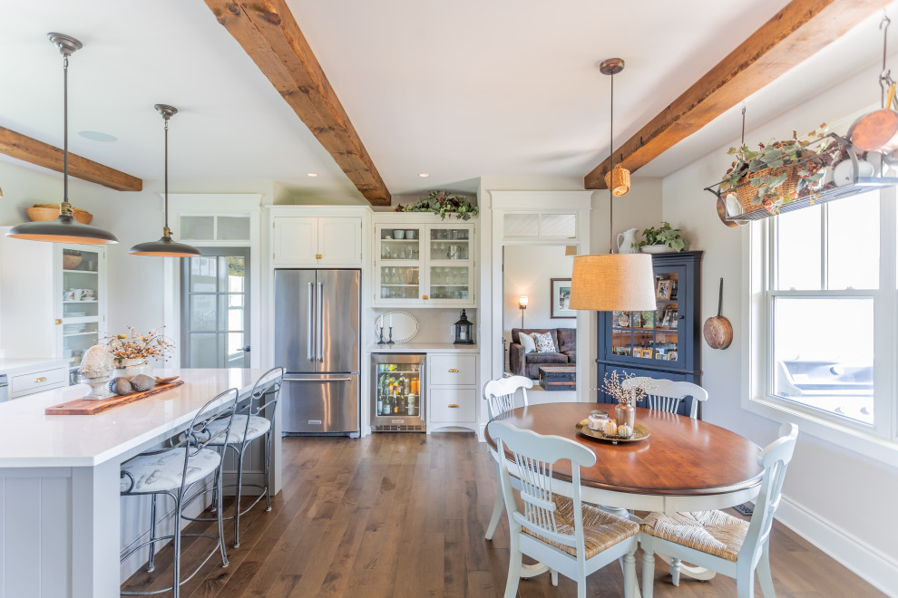 Large traditional l-shaped eat-in kitchen in Toronto with a farmhouse sink, flat-panel cabinets, white cabinets, quartz benchtops, beige splashback, stainless steel appliances, medium hardwood floors, with island, brown floor and white benchtop.