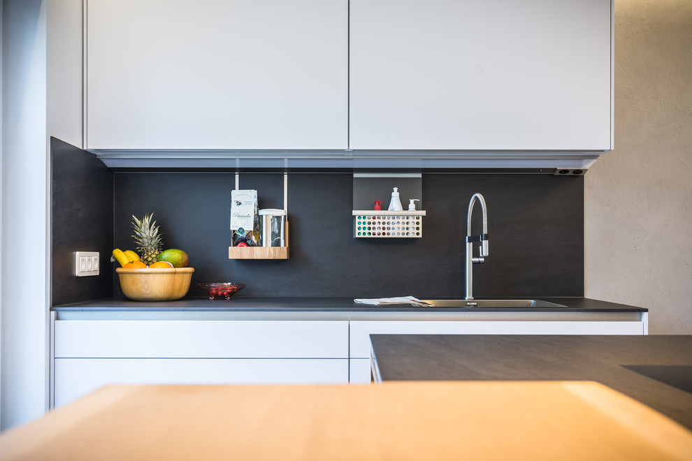 This is an example of a contemporary kitchen in Frankfurt with a single-bowl sink, white cabinets, black appliances and with island.