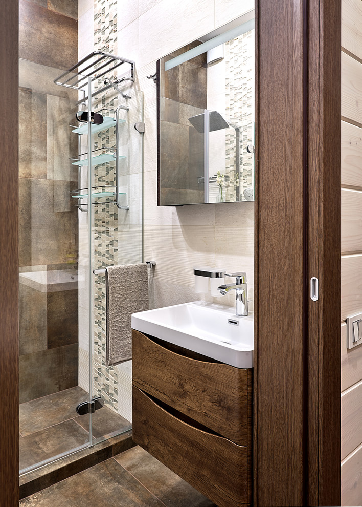 Inspiration for a mid-sized contemporary master bathroom in Moscow with flat-panel cabinets, medium wood cabinets, an alcove shower, a wall-mount toilet, brown tile, porcelain tile, beige walls, porcelain floors, a wall-mount sink, brown floor, a hinged shower door and white benchtops.