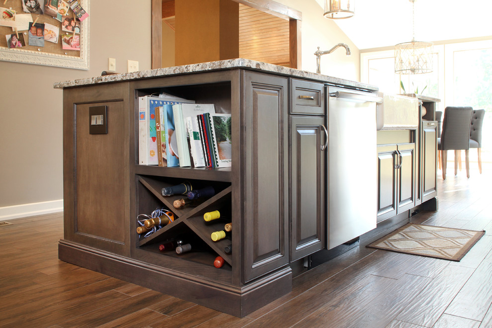 Inspiration for a large transitional l-shaped porcelain tile eat-in kitchen remodel with a farmhouse sink, granite countertops, white backsplash, ceramic backsplash, stainless steel appliances, an island, recessed-panel cabinets and gray cabinets